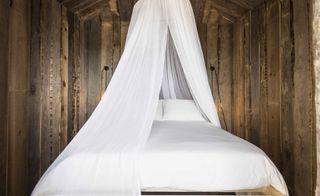 Wooden cabanas bedroom with white mosquito net hanging from the ceiling