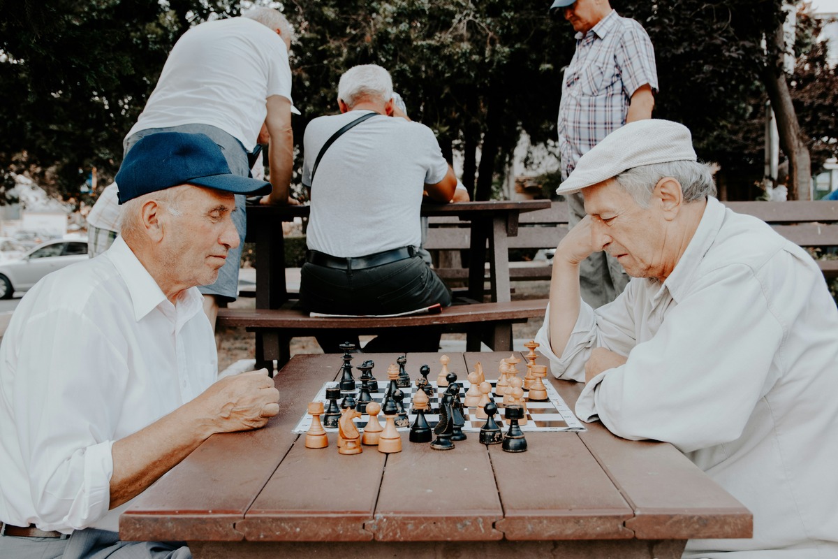 Two older white men playing chess at the park