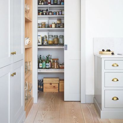 Kitchen area with a pantry on show behind a sliding door and wooden floors