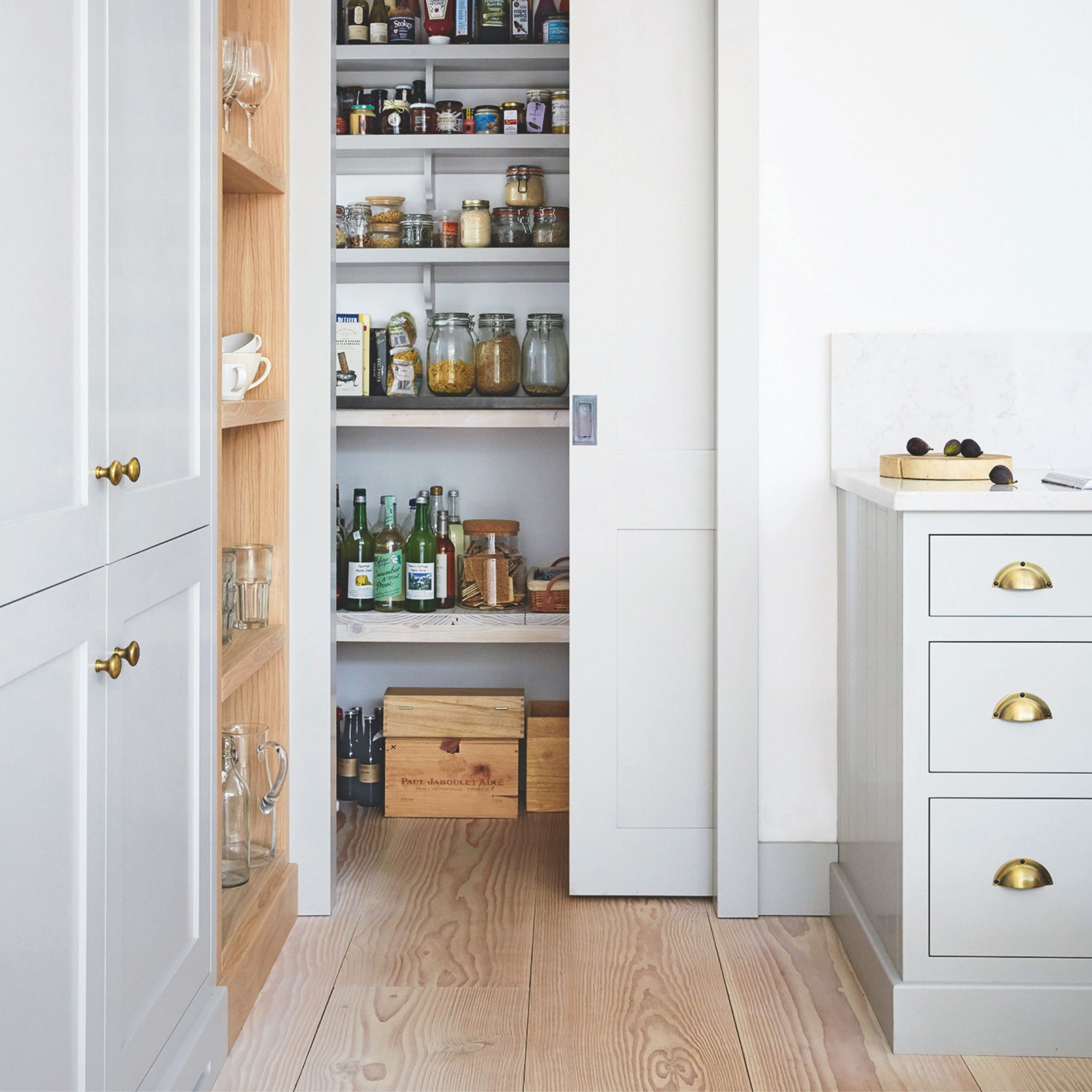 Kitchen area with a pantry on show behind a sliding door and wooden floors