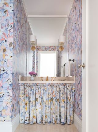 powder room with floral fabric curtains under basin and matching floral wallcovering with mirror