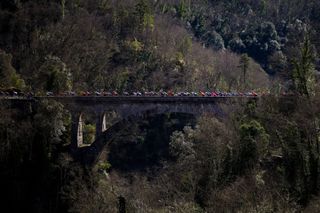 The pack of riders (peloton) cycles across a bridge over the Vesubie river during the 8th and final stage of the Paris-Nice cycling race, 119,9 km between Nice and Nice, on March 16, 2025. (Photo by Anne-Christine POUJOULAT / AFP)