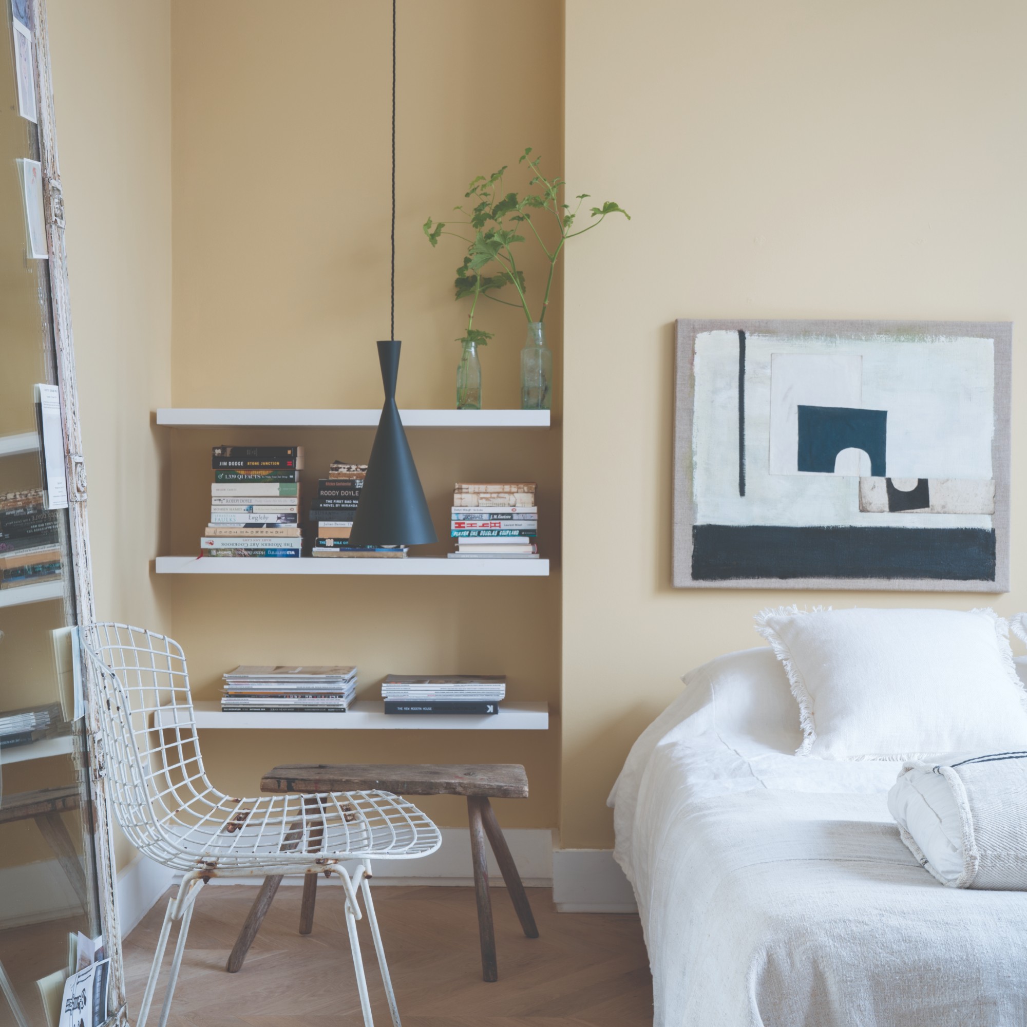 A bedroom painted in Farrow &amp;amp; Ball soft yellow Hay shade with open shelving in an alcove