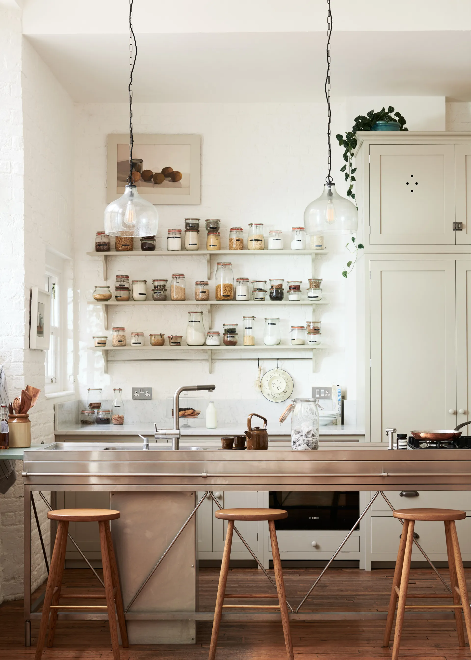 small minimalist utilitarian style kitchen with stainless steel island with a hob and sink