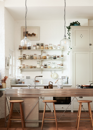 small minimalist utilitarian style kitchen with stainless steel island with a hob and sink