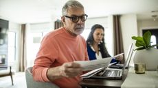 An older couple go over their finances together at the kitchen table.