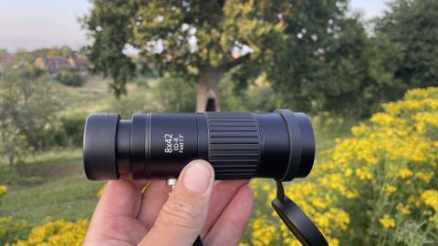 An Opticron Explorer WA ED-R 8x42 monocular held between the author&#039;s fingers.