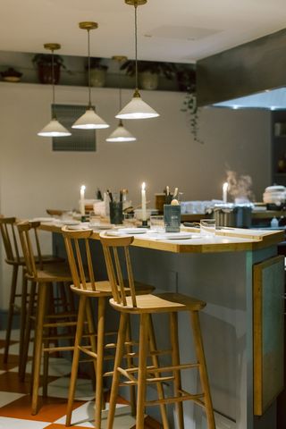 A view of the kitchen's counter with wooden chairs and cone-shaped lamps