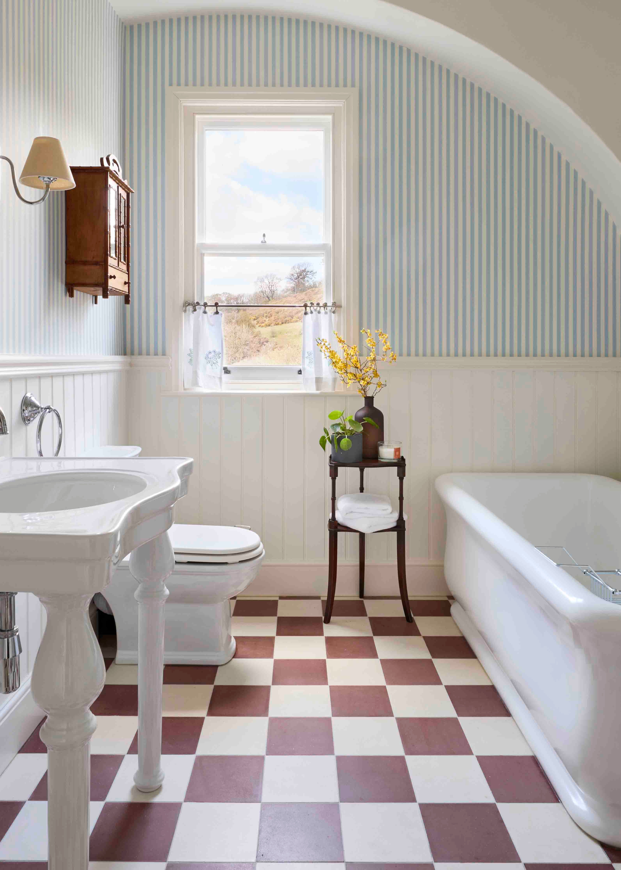 a red and white checkerboard floored bathroom with white and green striped tile walls and a freestanding tub