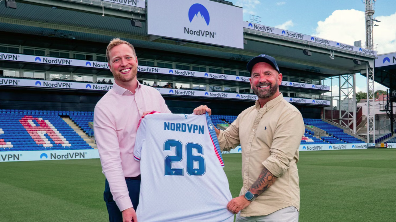 Crystal Palace and NordVPN's representatives holding holding a team's shirt named as NordVPN in the stadium's pitch