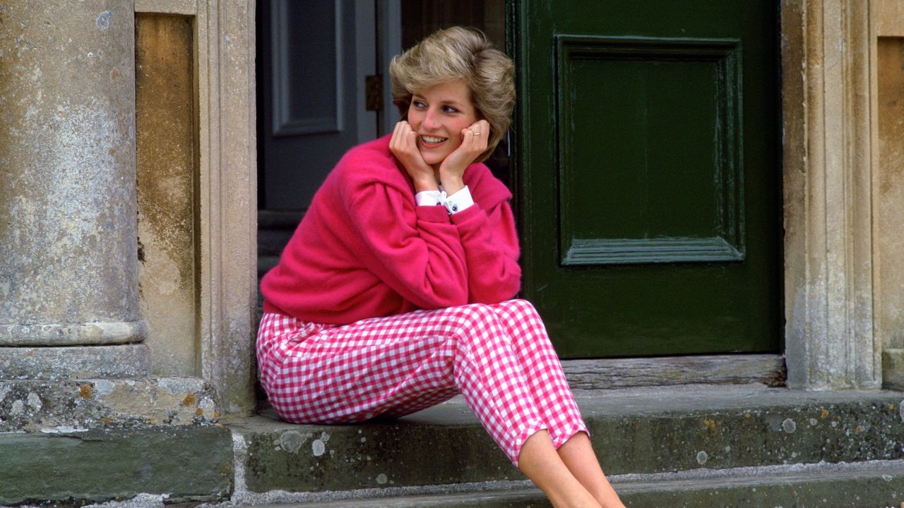 Diana, Princess Of Wales, Sitting On The Steps Outside Her Country Home, Highgrove. The Princess Is Casually Dressed In Pink Gingham Trousers With A Matching Pink Jumper