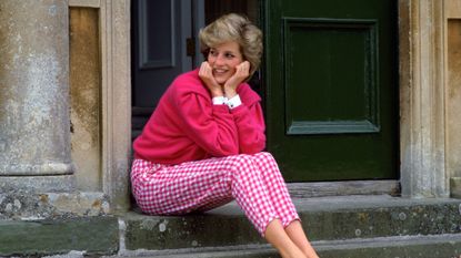Diana, Princess Of Wales, Sitting On The Steps Outside Her Country Home, Highgrove. The Princess Is Casually Dressed In Pink Gingham Trousers With A Matching Pink Jumper