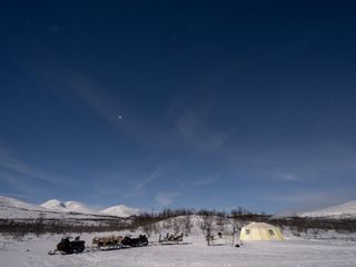 northern lights tour set up Abisko shows a clear star-studded sky snowmobiles below.