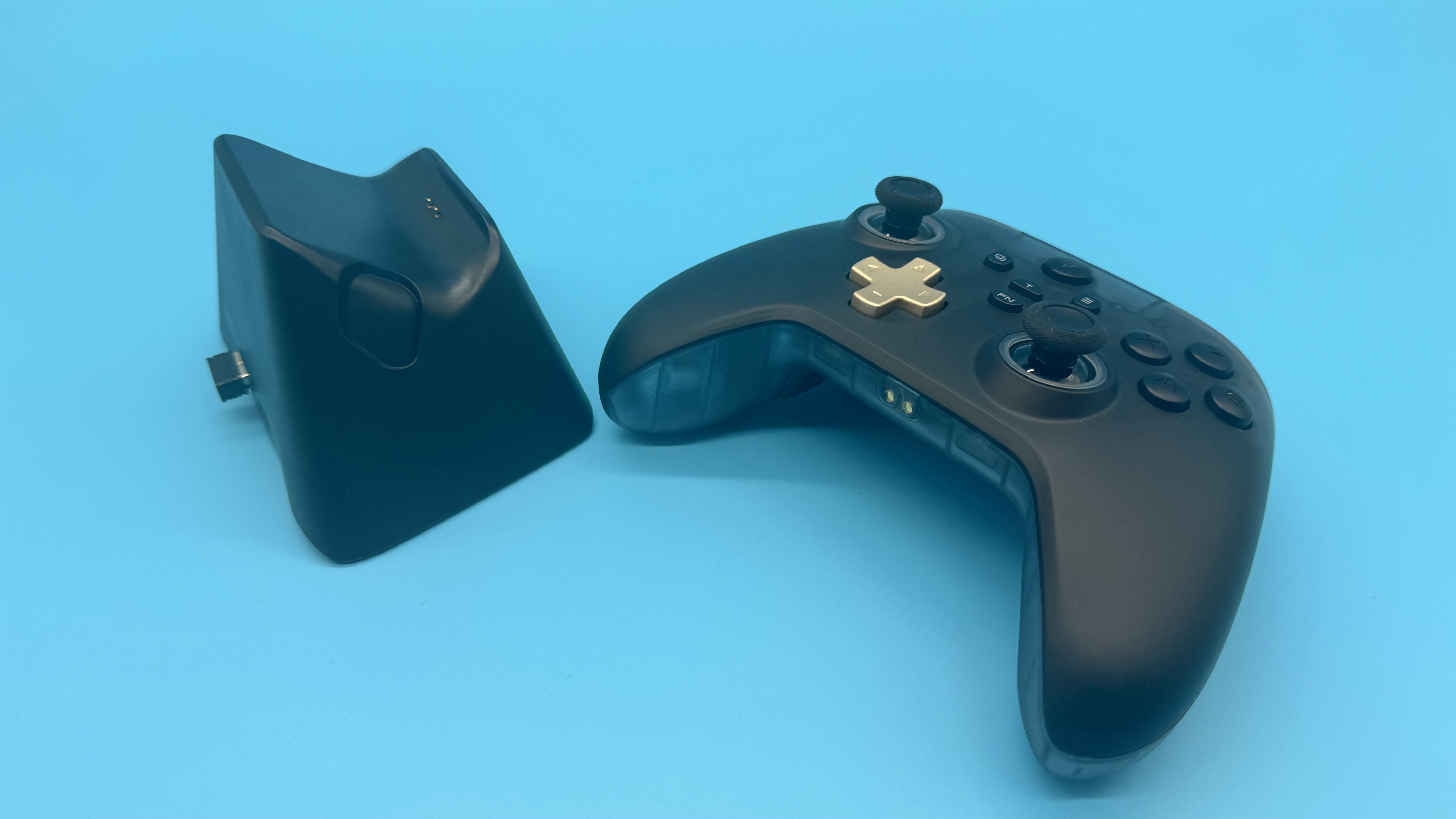 EasySMX D05 black gaming controller next to its charging stand on a blue background