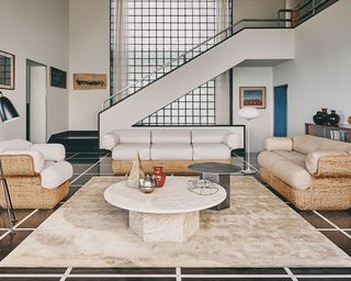 Sofa and lounge chair set in large living room, large cream rug, round marble coffee table, neutral palette