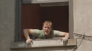 A still from Stress Positions movie of a character leaning out of a window and shouting.