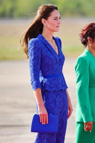 Kate Middleton carries a blue clutch bag as she arrives at Philip S. W Goldson International Airport on March 19, 2022 in Belize City, Belize.