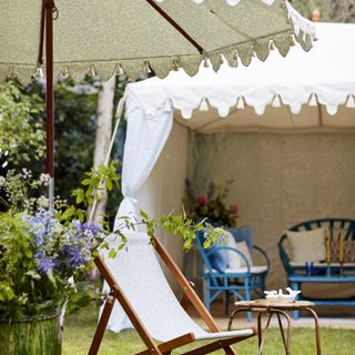 Outdoor fabric tent in a garden next to a parasol.