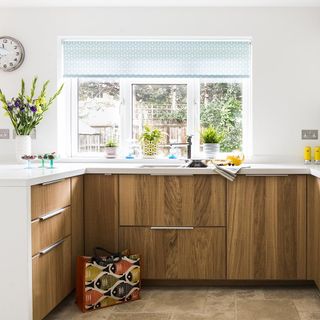 a bright kitchen with wooden cabinets flowers and plants on the work surface