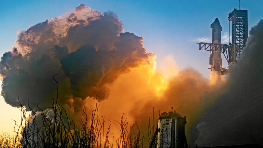 A SpaceX rocket lifts off in the background behind the a plume of fiery smoke.