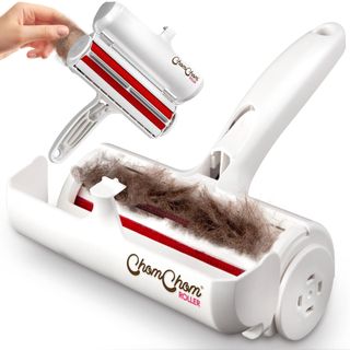 A white pet hair remover filled with brown pet hair with a hand holding it in the background