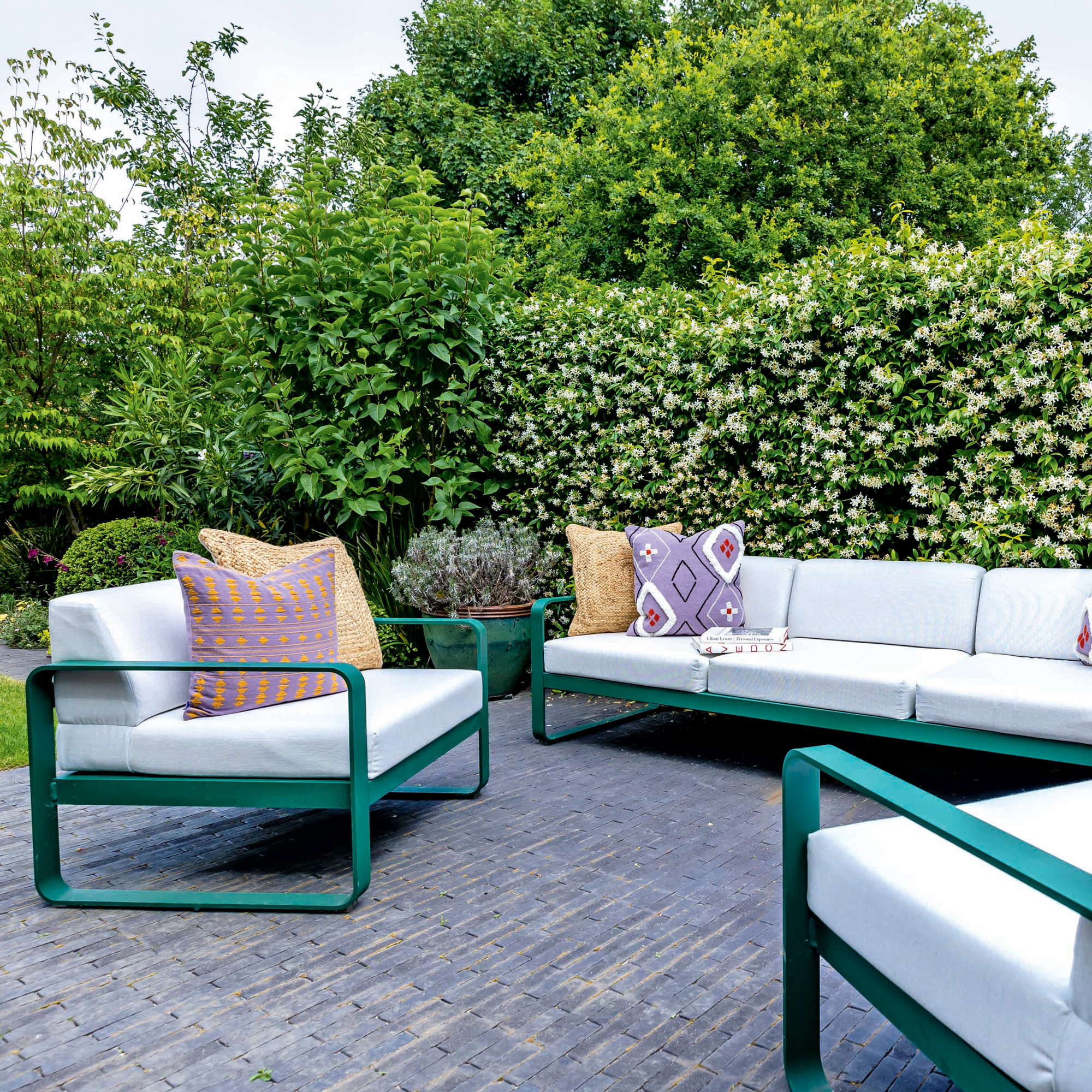 garden makeover with green and white outdoor sofa and armchairs on a grey tiled patio