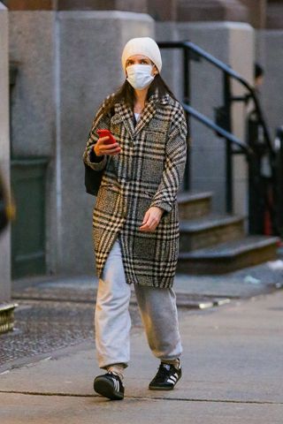 Katie Holmes wearing a grey and black coat with grey sweats and Adidas Samba sneakers