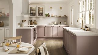 pink kitchen with white worktops and wooden floors