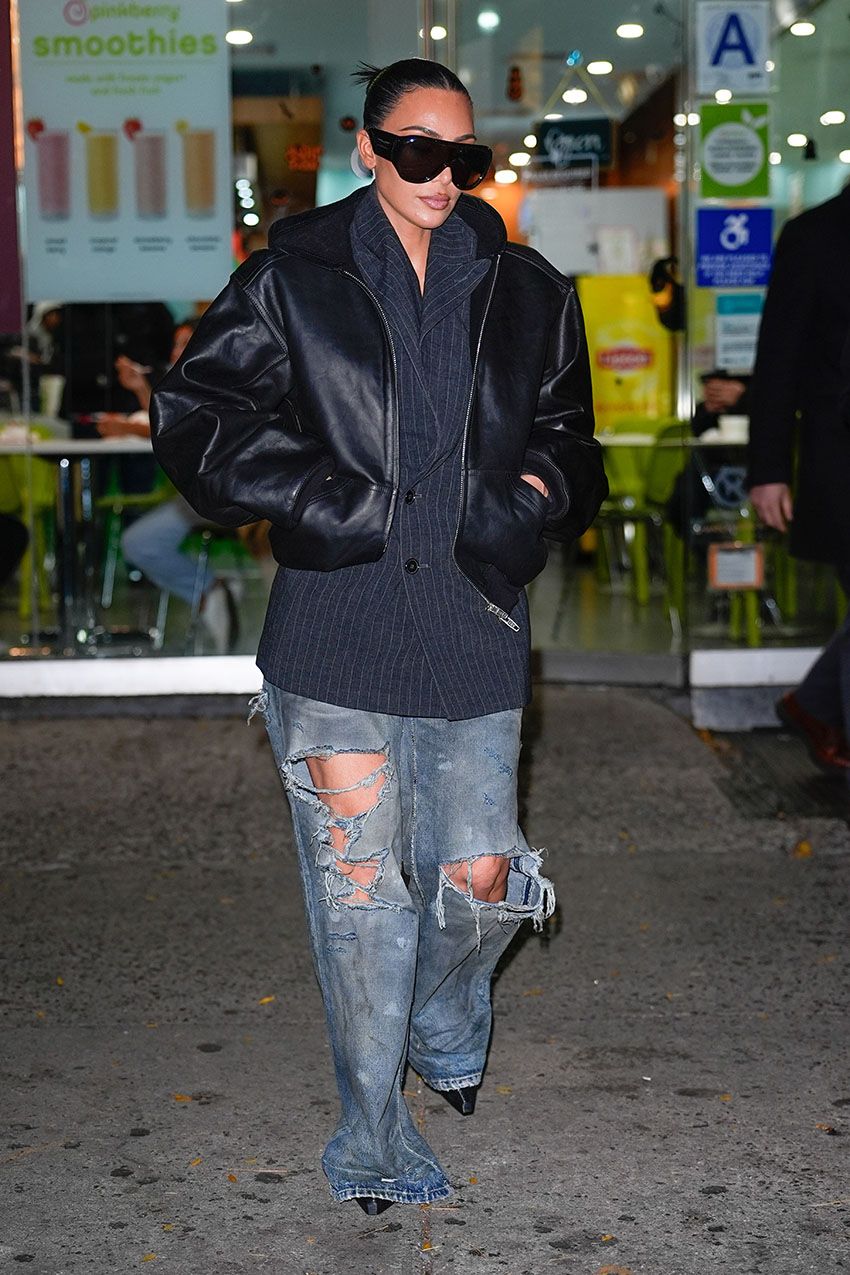 Kim Kardashian wearing a black leather jacket, pinstripe blazer, and ripped jeans