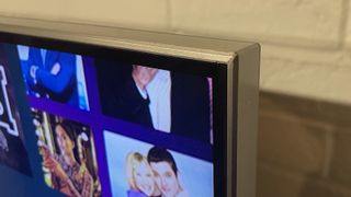 En Samsung QN95B QLED TV på en TV-bänk, inzoomat på det övre högra hörnet av TV:n.