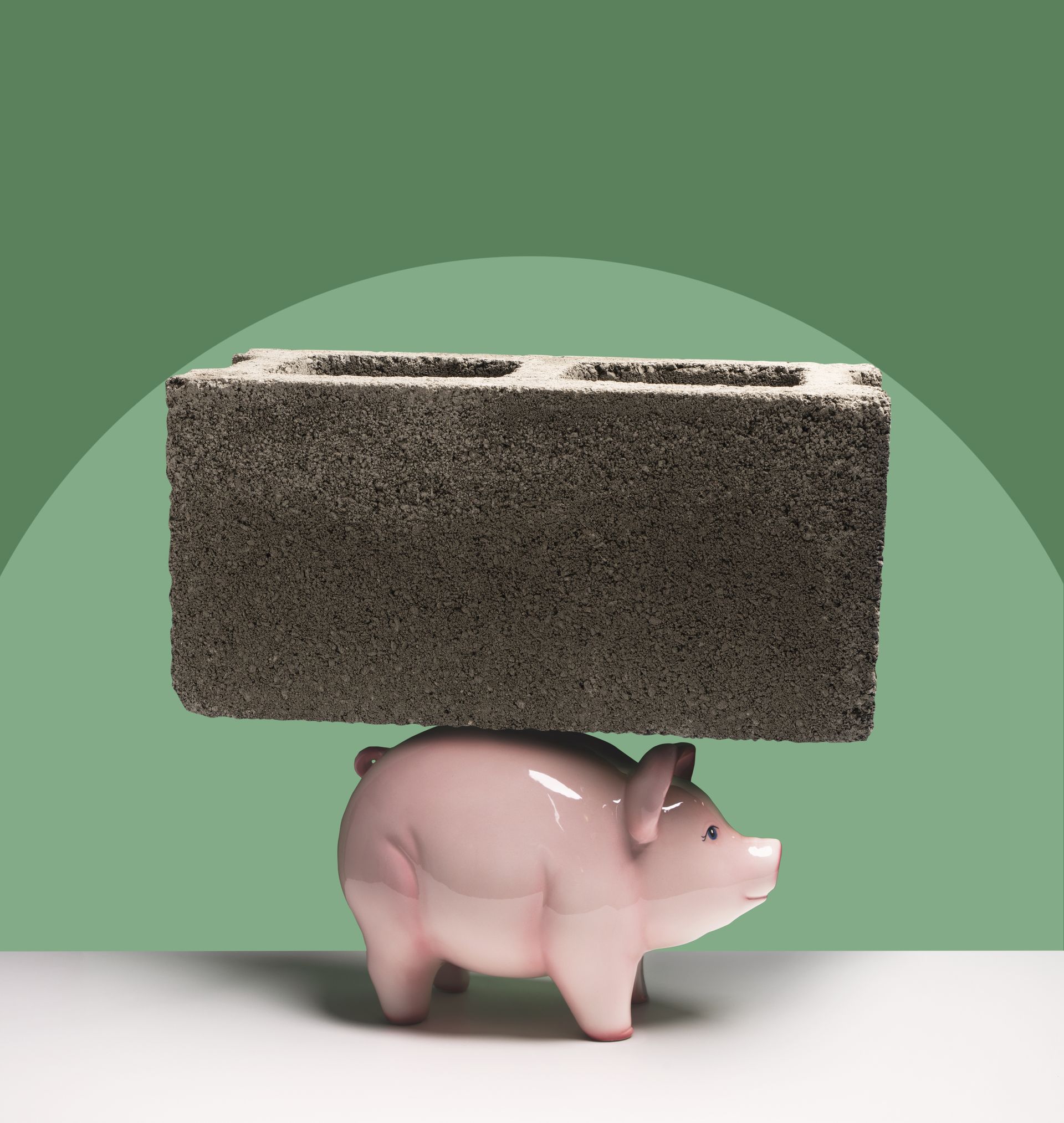 A ceramic piggy bank with a large cinder block sitting on top of it.