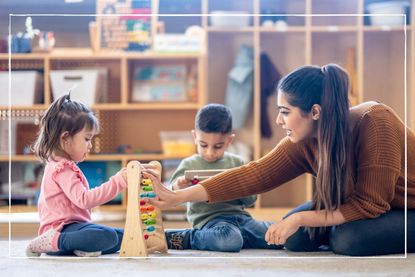 nursery working sitting on floor engaging children playing with abacus at nursery