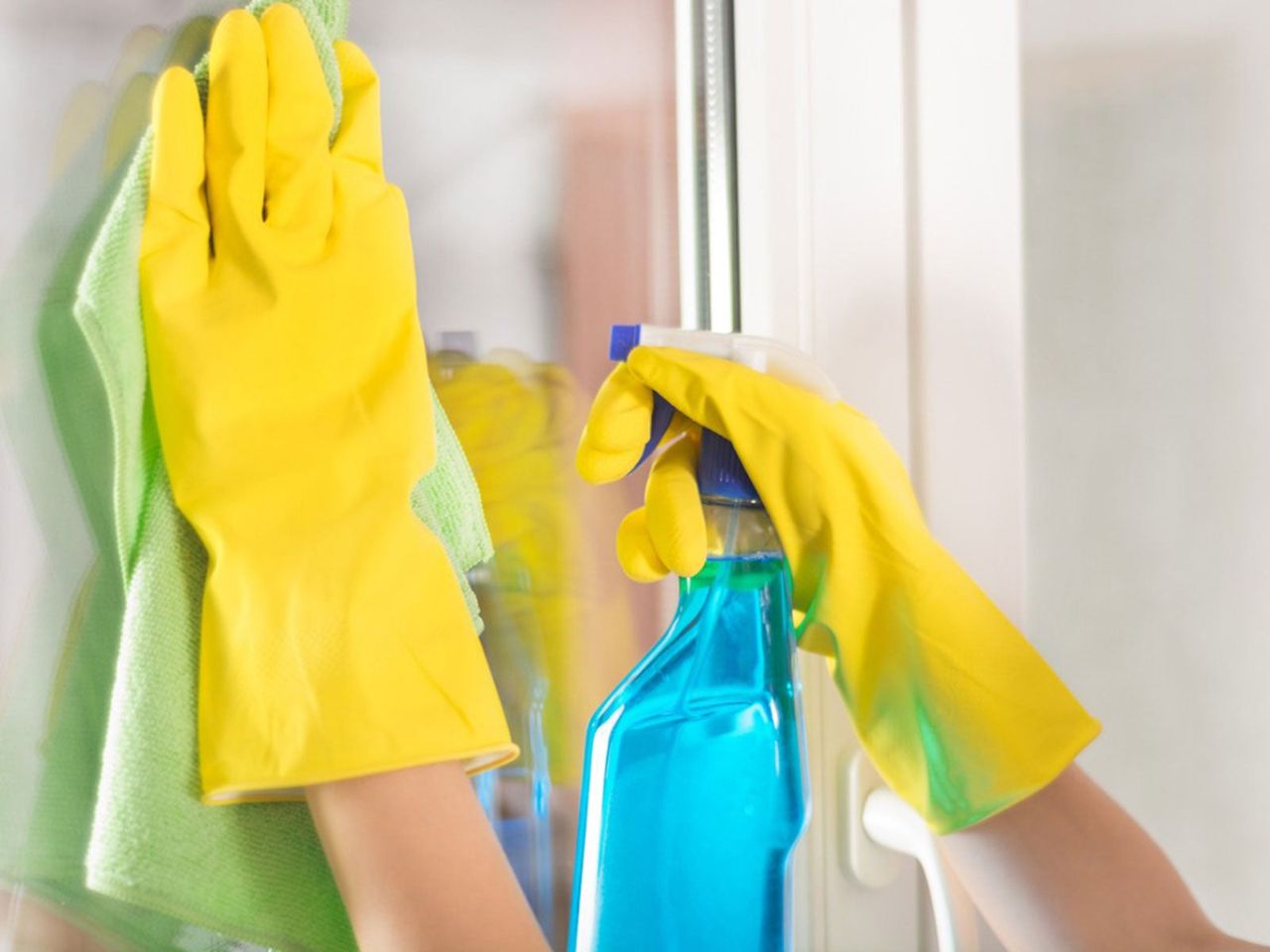 Cleaner With Gloves Spraying A Window