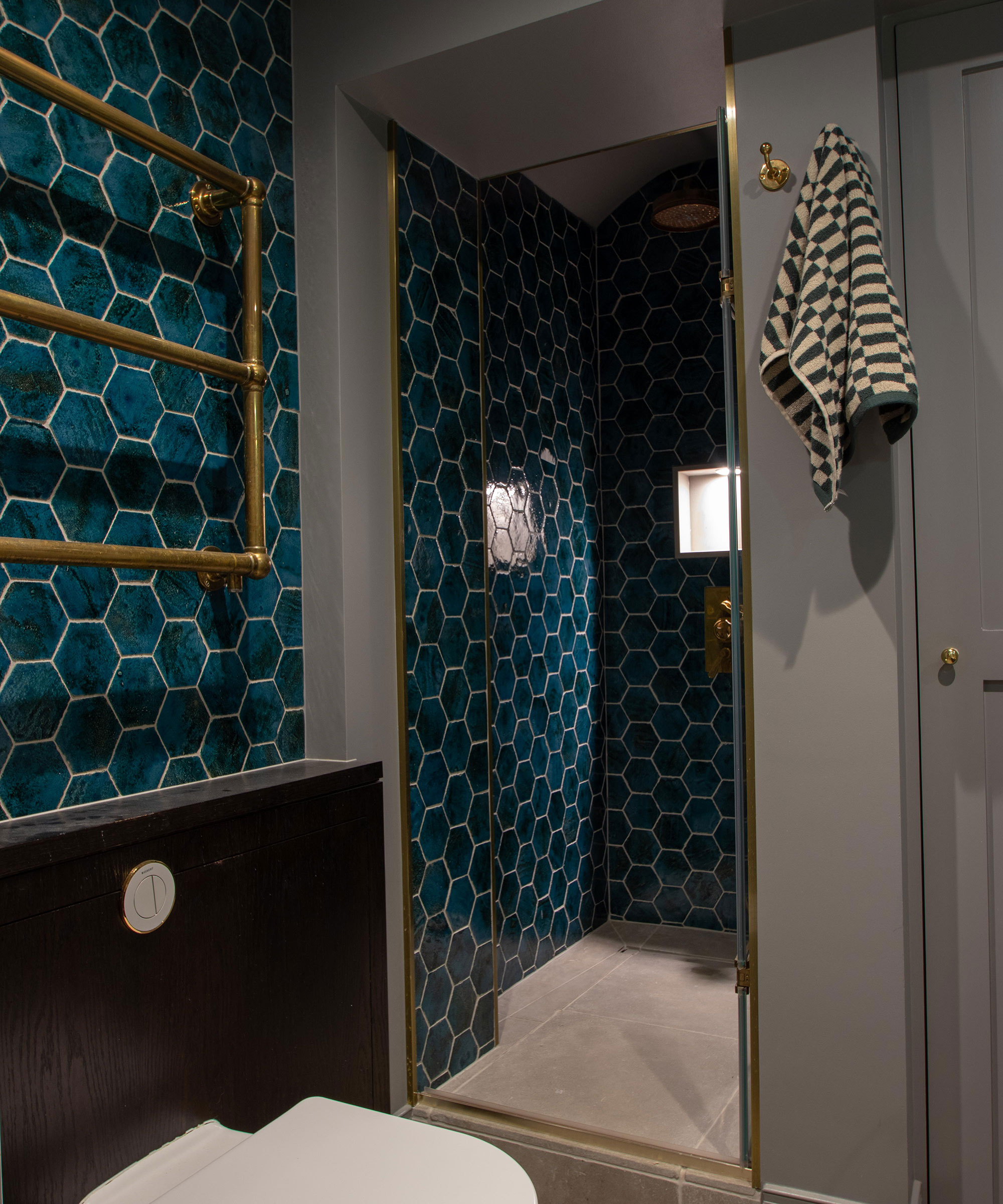 small bathroom with walk-in shower and grey walls with blue hexagonal wall tiles