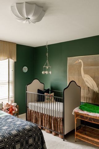 gender neutral nursery with green walls, black cot, stock artwork, blind