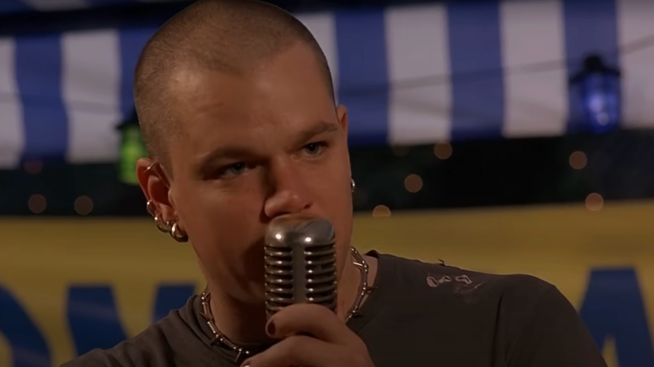 A pierced and shaved Matt Damon speaks into an old school mic on stage in Euro Trip.