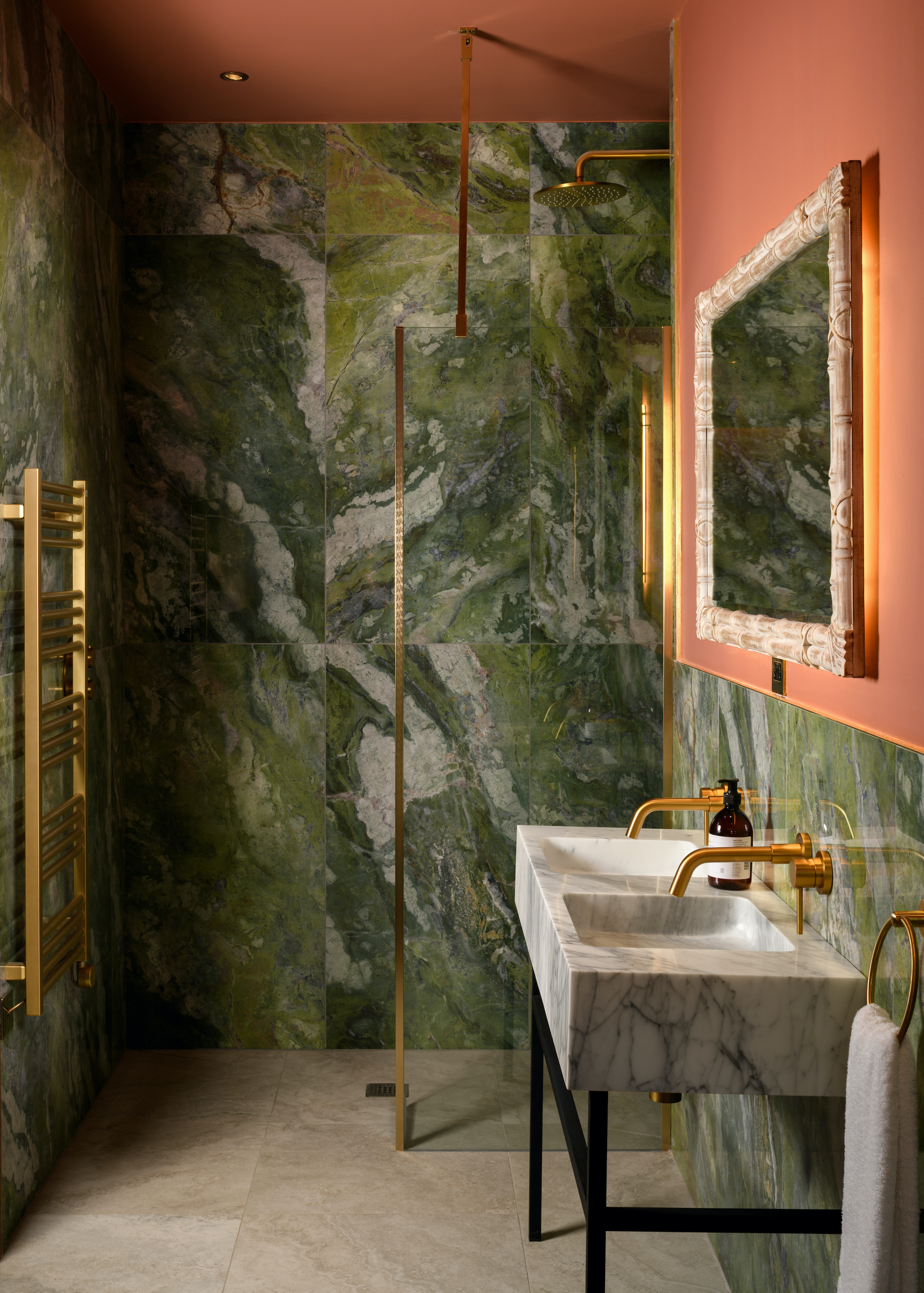 small ensuite bathroom with swirly green marble and coral walls