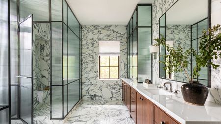 modern marble bathroom with glass walls, double vanity and curtain over window