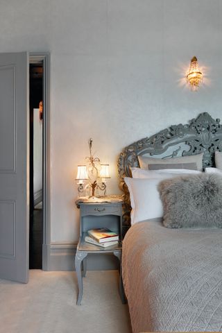 Luxurious grey bedroom with ornate bed and glass wall light