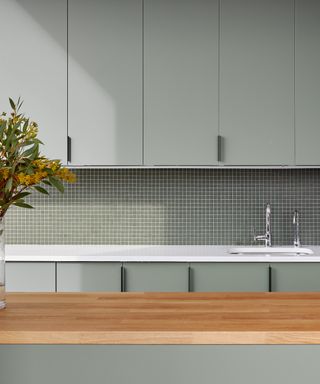 kitchen countertop trends, sage green kitchen with wooden kitchen island, white countertop, mosaic tiled backsplash