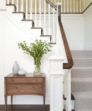 An entryway staircase painted white and a wooden console table