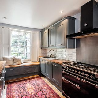 kitchen with dark green cupboards and vibrant rug