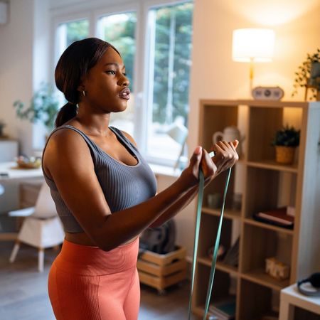 A woman doing an advanced resistance band arm workout at home in her living room