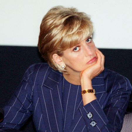 Princess Diana wearing a blue suit resting her chin on her hand