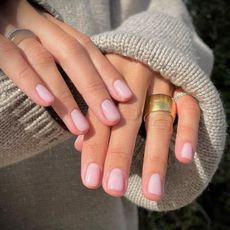 A woman wearing the OPI nail polish called Love Is In The Bare