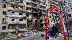 A child on a swing outside a building in Kyiv damaged by a missile in February 2022