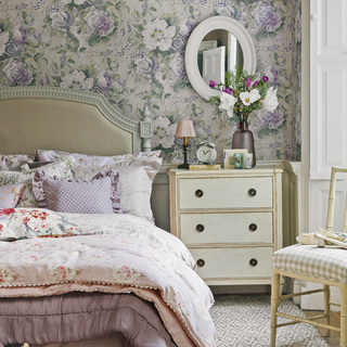 bedroom with floral wallpaper bed with cushions drawer sidetable