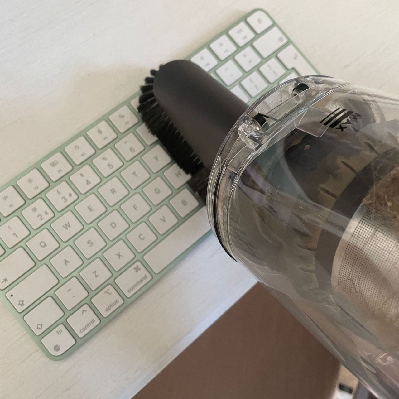 Using the dusting brush on a green and white computer keyboard