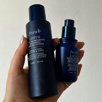 hand holding fresh lotus toner and serum bottles