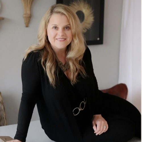 Image of a woman dressed in all black leaning on a white table.